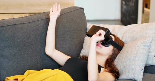 Woman Immersed in Virtual Reality Lying on Couch