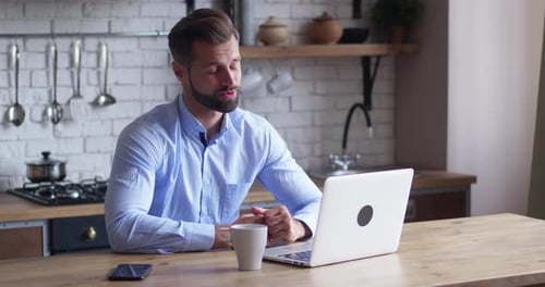 Man Using Laptop for Video Call in Kitchen