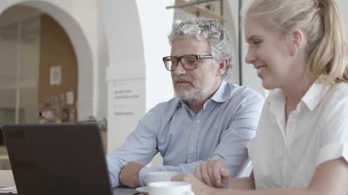 Colleagues Collaborate on Laptop in Modern Office