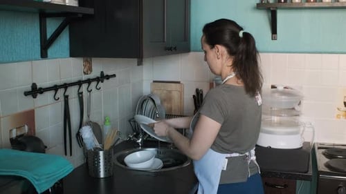 Young Woman Washing Dishes in the Kitchen