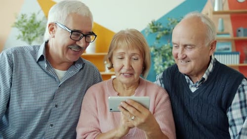 Three Happy Seniors Using a Smartphone Together Indoors