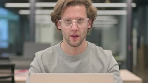 Man Gives Thumbs Up Using Laptop in Office