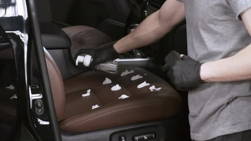 Man Detailing Car Seat With Cleaning Foam