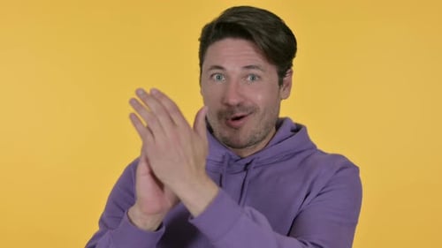 Positiver Mann klatscht, gelber Hintergrund