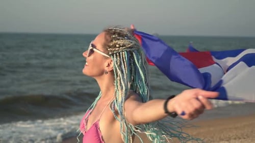 Woman Smiling on Beach with a Colorful Flag