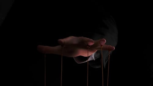 Puppet Master steuert und manipuliert die Puppen mit Schnüren, die an seinen Finger befestigt sind