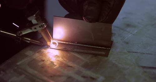 Welder fusing metal pieces in dark environment