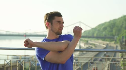 Man Stretching Arms Before Workout on Bridge