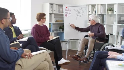 Senior Teacher Giving Lecture to Young Adults in Office