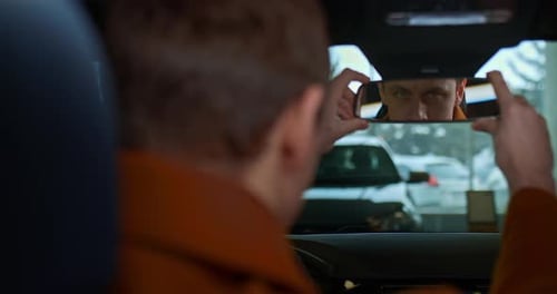 Portrait Reflection of a Male Driver in the Rearview Mirror in a New Car