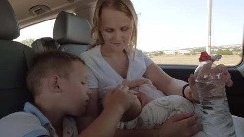 Woman Nursing Infant in Car with Child