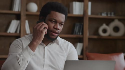 Man Talking on Phone While Working on Laptop