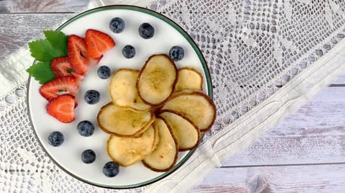 Fried Pancakes on Plate with Strawberries and Blueberries Rotate Slowly on Turntable