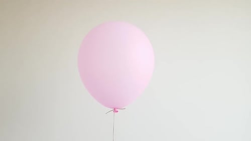 Single Pink Balloon Gently Floating, White Backdrop