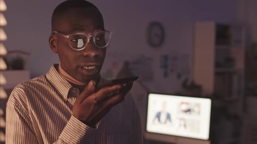African-American Man Recording Voice Message in Dark Office