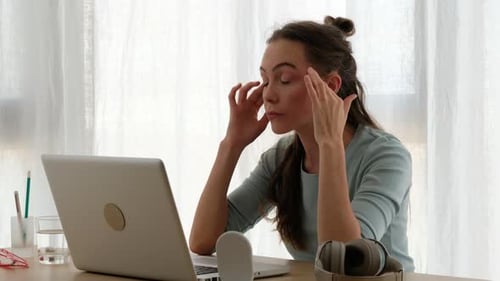 Exhausted Woman Working on Laptop at Desk