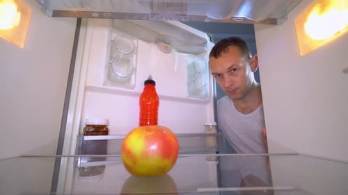 Man Opens Refrigerator and Takes an Apple