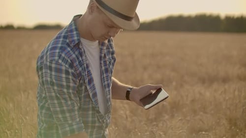 Young Male Farmer Holding Tablet in Wheat Field