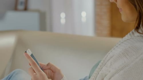 Woman Using Smartphone on Couch Indoors