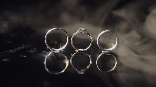 Elegant Wedding Rings Reflecting on Dark Surface