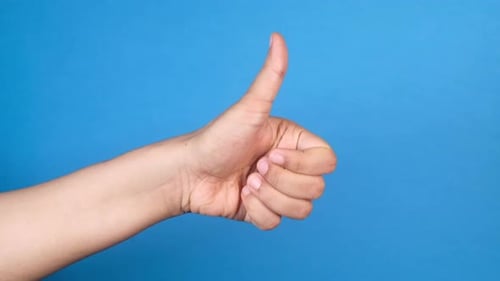 Hand Gives a Thumbs Up on Blue Background