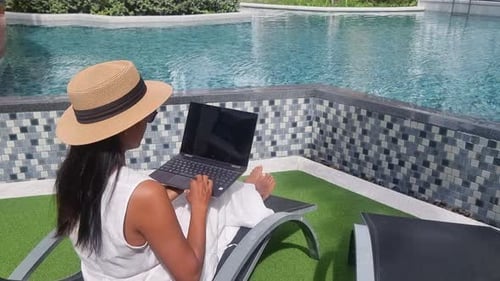 Asiatische Frauen mit Hut überprüfen Laptop im Urlaub Digital Nomad Concept
