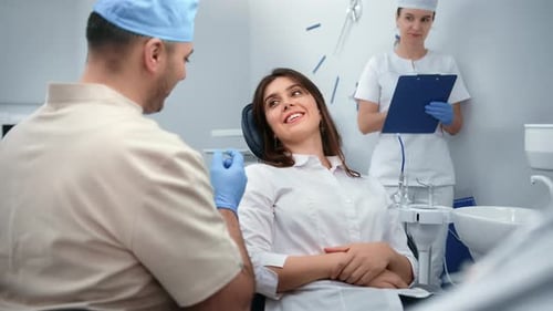 Smiling Female Patient Consulting Male Dentist at Regular Medical Checkup Clinic