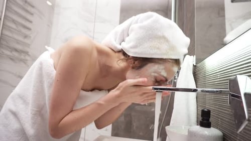 Woman Washing Face with Mask in Modern Bathroom