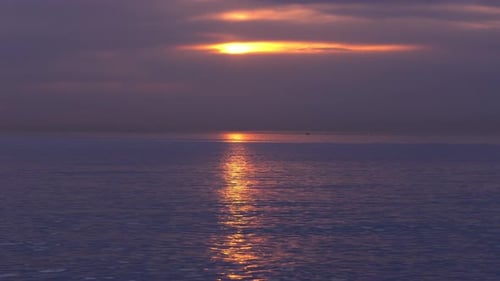 Rote Sonnenuntergänge über dem Meer Video. Sonne am Horizont bricht hinter Wolken durch.
