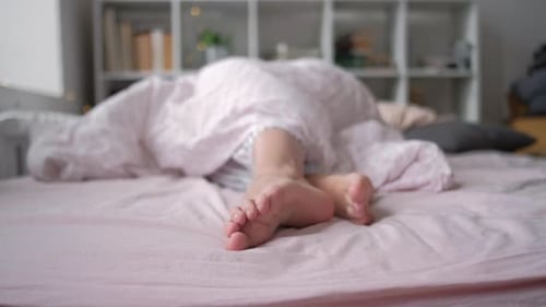 Closeup View of Feet Lying on Soft White Pillow at Bed