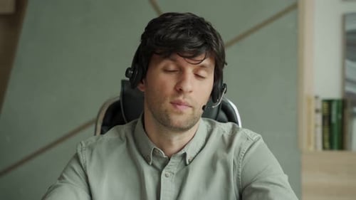 Man in a Shirt is Using a Headset in the Office a Man is Looking and Talking Into the Camera While