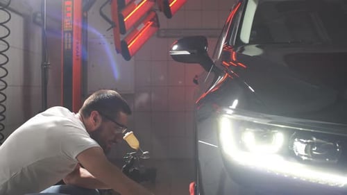 Man Worker Polishing Car on a Car Wash.