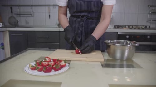 Woman cuts strawberries on cutting board