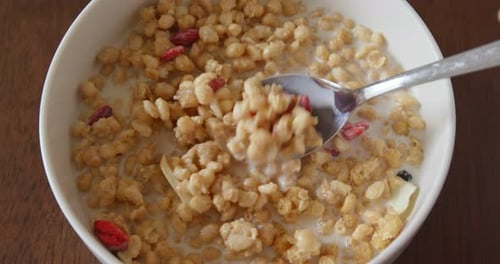 Cereal Bowl with Fruit and Milk Stirring Close Up