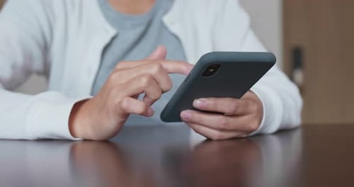 Adult Using Smart Phone at Table Indoors