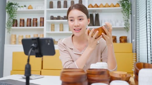 Asian business woman sell vase product online live streaming at home. Remote buying and purchase.
