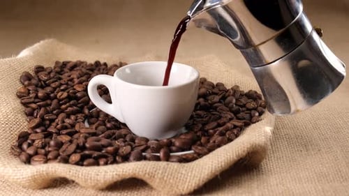 Fresh Coffee Pouring into Cup With Coffee Beans