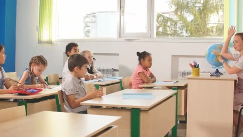 Group of School Children All Raising Their Hands in the Air To Answer