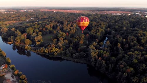 A beautiful red balloon flies in the evening over the river and the city