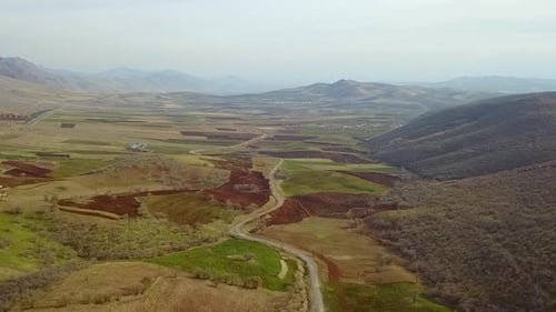 Beautiful green field with cinematic landscape, farm and fields in the mountains foothills with some
