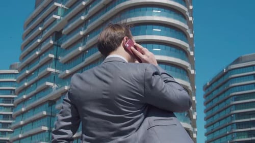 Man Talking on Phone Outside Modern Office Building