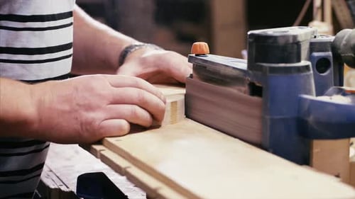 Handwerker, der mit Schleifmaschine in der Holzwerkstatt arbeitet, Hände Nahaufnahme.