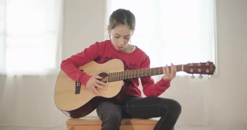 Young Girl Plays Guitar and Sings Indoors