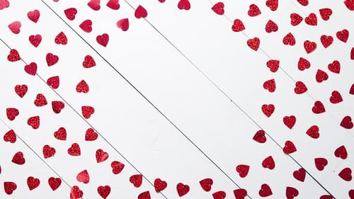 Vlentine's Day Composition. Heart Shaped Sequins Placed on White Wooden Table