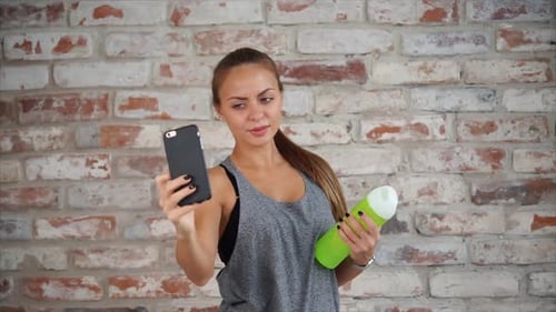 Young Woman Posing with Water Bottle and Phone