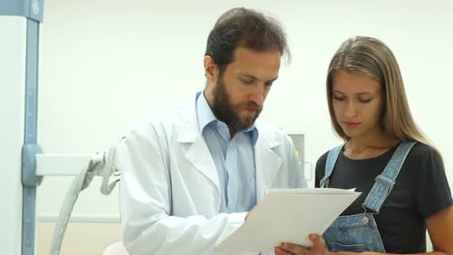 Doctor Discussing Paperwork With Patient in Hospital