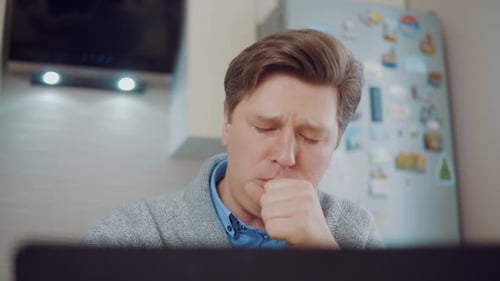 Tired Man Yawns in Front of Laptop