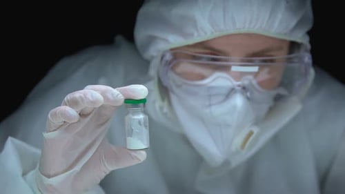 Scientist Examining Rat and Vial in Hazmat Suit