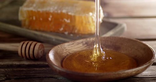 Fresh Honey Pours Into a Plate on the Table.