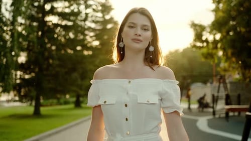 Portrait of an Attractive Young Woman Walking in the Park at Sunset